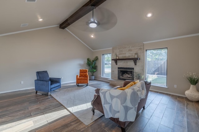 living room with vaulted ceiling with beams, a stone fireplace, ornamental molding, and a healthy amount of sunlight