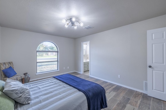 bedroom featuring hardwood / wood-style flooring, ensuite bathroom, and a textured ceiling