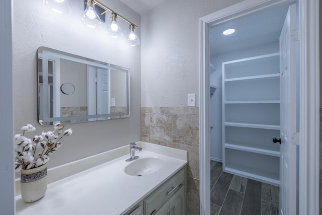 bathroom featuring hardwood / wood-style floors, vanity, and tile walls