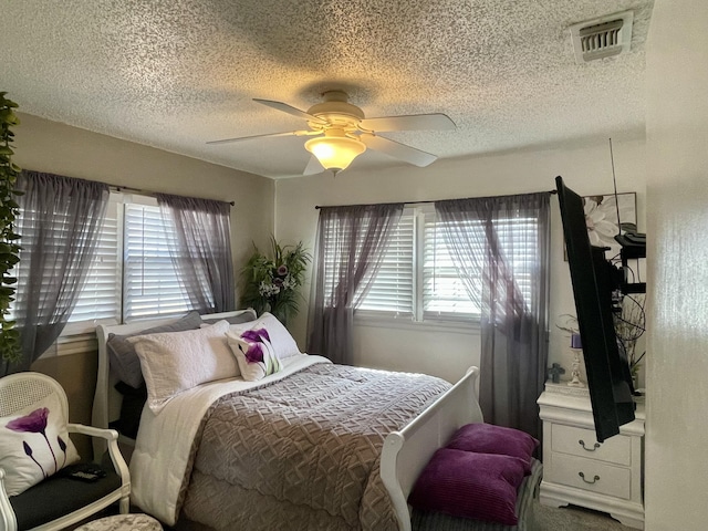 bedroom featuring ceiling fan, a textured ceiling, and visible vents