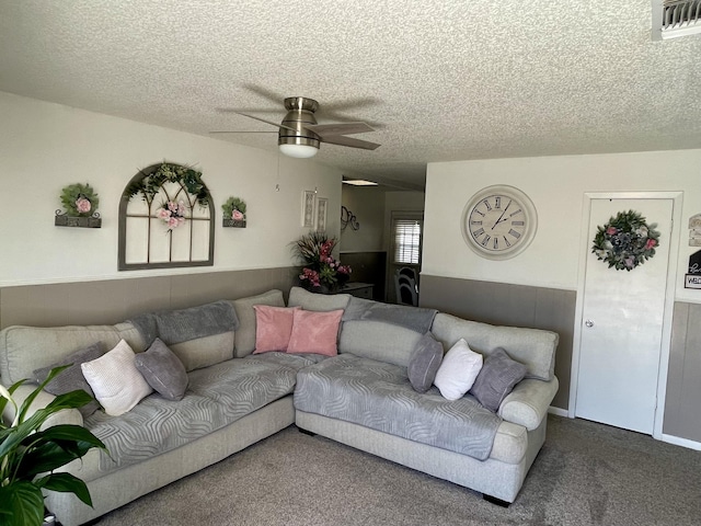 carpeted living room with wainscoting, a ceiling fan, a textured ceiling, and visible vents