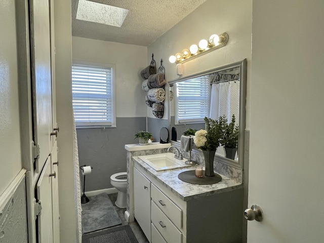 bathroom featuring a wealth of natural light, toilet, a textured ceiling, and a skylight