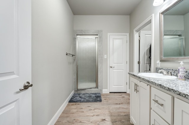 bathroom with an enclosed shower, vanity, and wood-type flooring