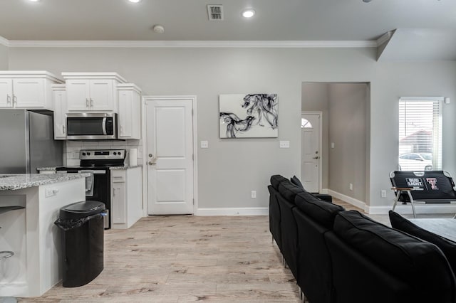 kitchen with light stone counters, stainless steel appliances, light wood-type flooring, and white cabinets