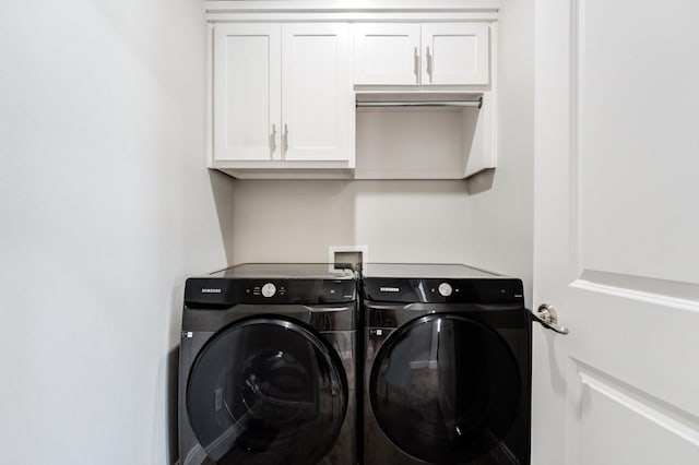 clothes washing area with cabinets and washing machine and clothes dryer