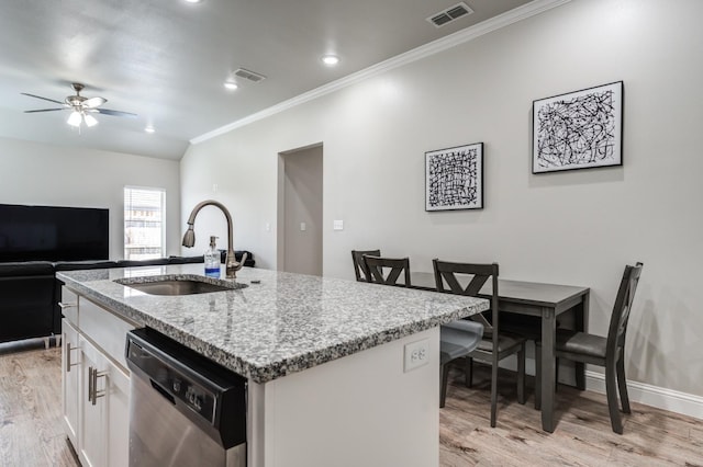 kitchen featuring an island with sink, sink, white cabinets, stainless steel dishwasher, and light stone countertops