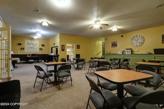 carpeted dining room featuring a textured ceiling and ceiling fan