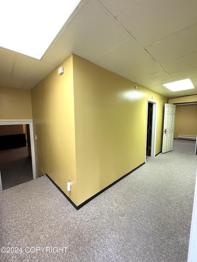 corridor with a baseboard heating unit and carpet flooring