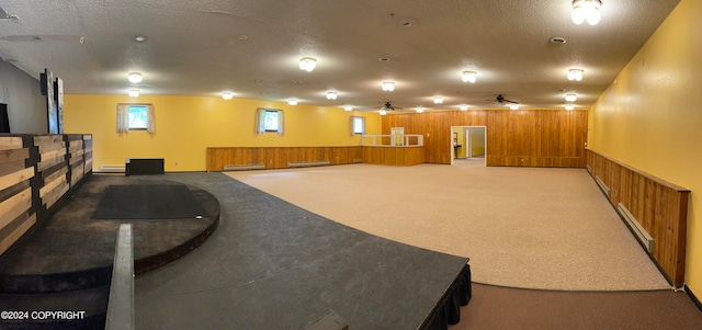 interior space featuring a baseboard heating unit, ceiling fan, carpet floors, and a textured ceiling