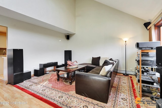 living area with baseboards, high vaulted ceiling, and wood finished floors