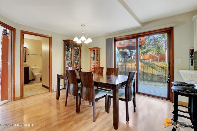 dining space featuring baseboard heating, a notable chandelier, baseboards, and light wood finished floors