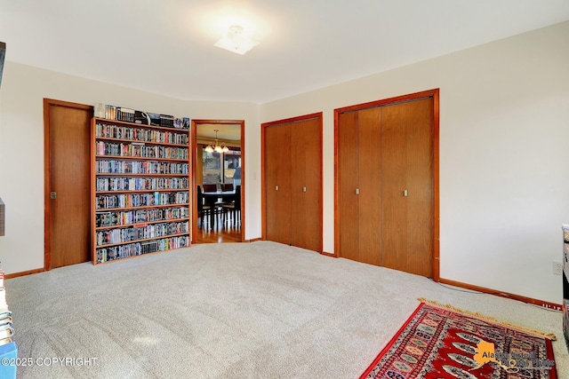 interior space featuring carpet flooring, baseboards, and an inviting chandelier