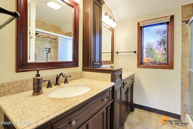 bathroom with lofted ceiling, a shower stall, tile patterned flooring, baseboards, and vanity