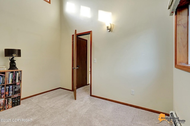 interior space with a baseboard radiator, baseboards, and light colored carpet