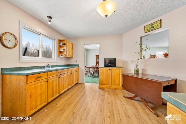 kitchen featuring a textured ceiling, light wood-type flooring, and sink