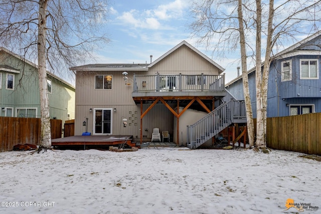 snow covered property with fence, a wooden deck, and stairs