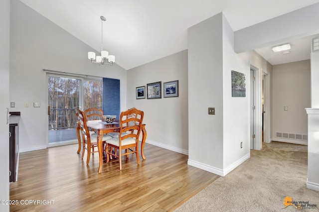 dining room with lofted ceiling, visible vents, baseboards, light wood finished floors, and an inviting chandelier