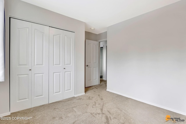 unfurnished bedroom featuring light carpet, a closet, and baseboards