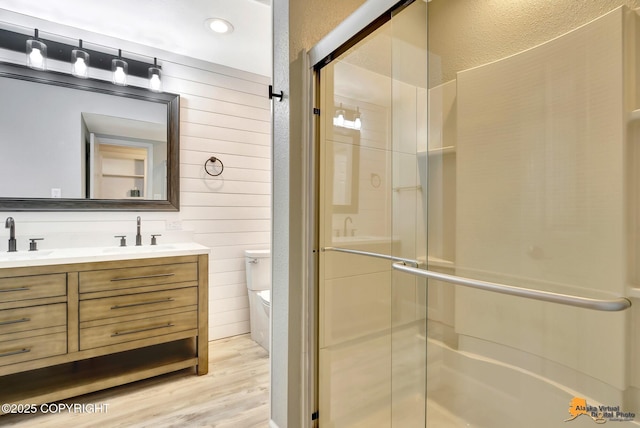 full bathroom with toilet, a shower stall, double vanity, and a sink