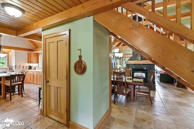 33405 Keystone Dr, Soldotna, AK 99669 - dining area with stone tile flooring, a fireplace, a wood ceiling with exposed beams, and a chandelier