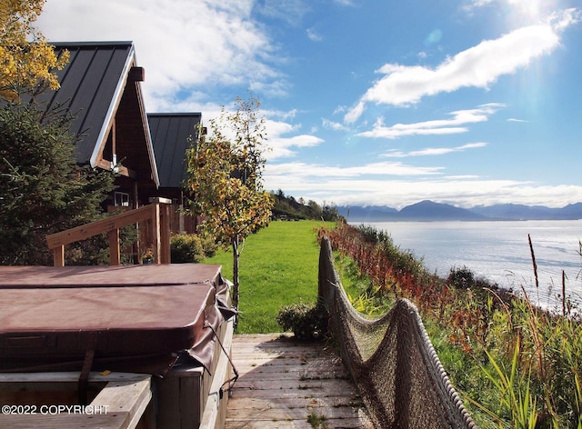 view of yard with a deck with water view and a hot tub