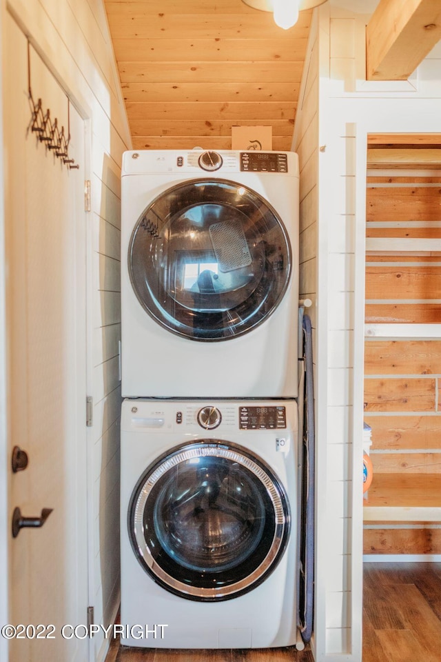 washroom featuring wood walls, wooden ceiling, stacked washing maching and dryer, and hardwood / wood-style flooring