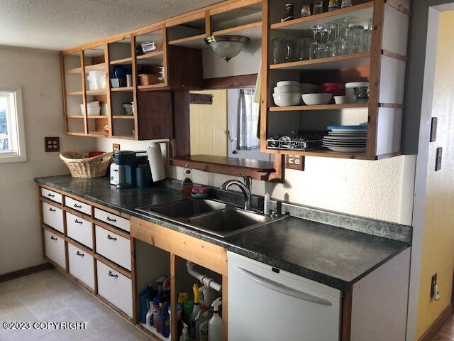 kitchen featuring white cabinetry, sink, white dishwasher, and a textured ceiling