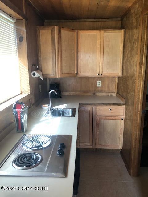 kitchen with wooden ceiling, white electric stovetop, sink, and dark tile patterned floors