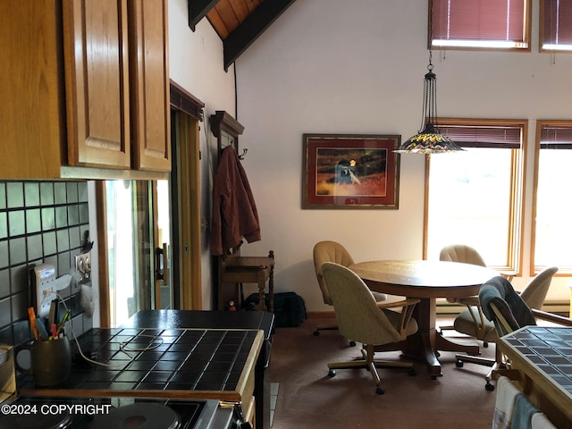 carpeted dining room featuring high vaulted ceiling and beam ceiling