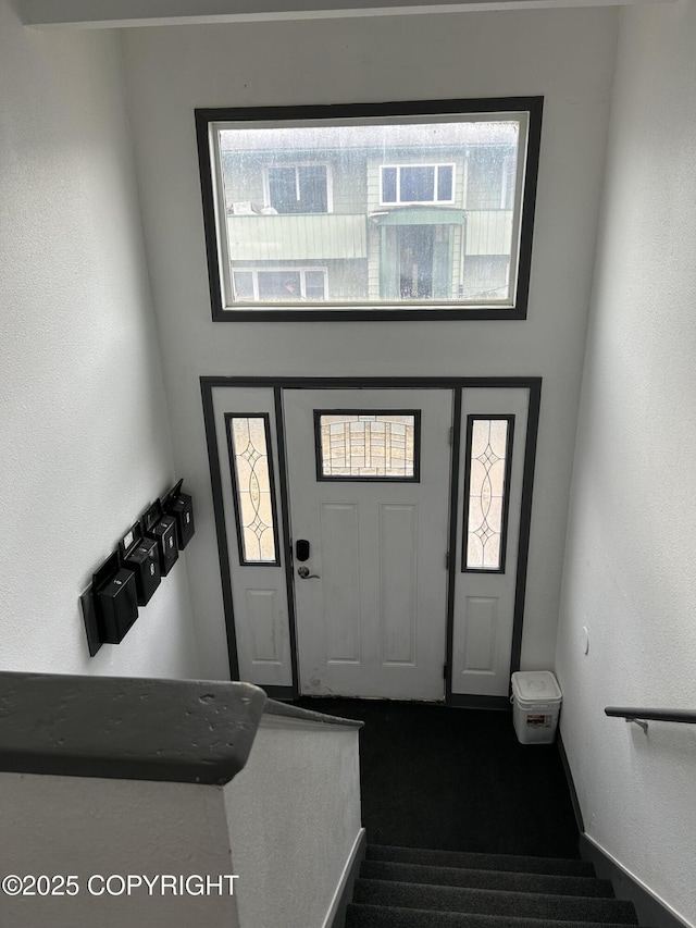 3940 E 9th Ave, Anchorage, AK 99508 - entrance foyer featuring baseboards, dark colored carpet, and stairs