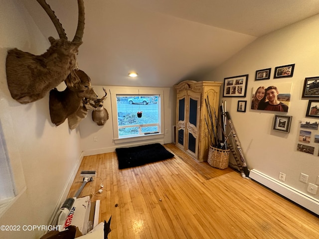 interior space featuring lofted ceiling, a baseboard heating unit, and light wood-type flooring