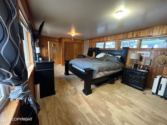 bedroom featuring light wood-type flooring and wood walls