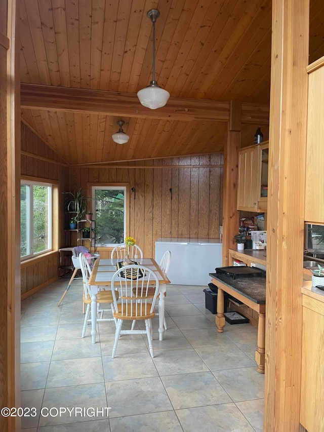 dining room with light tile floors, wooden walls, vaulted ceiling with beams, and wooden ceiling