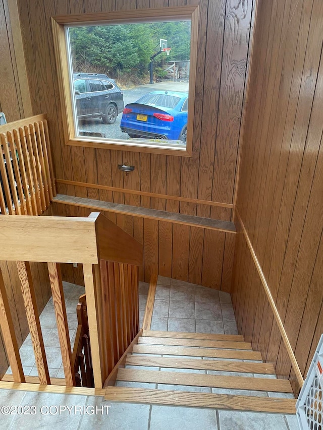 stairway featuring wood walls