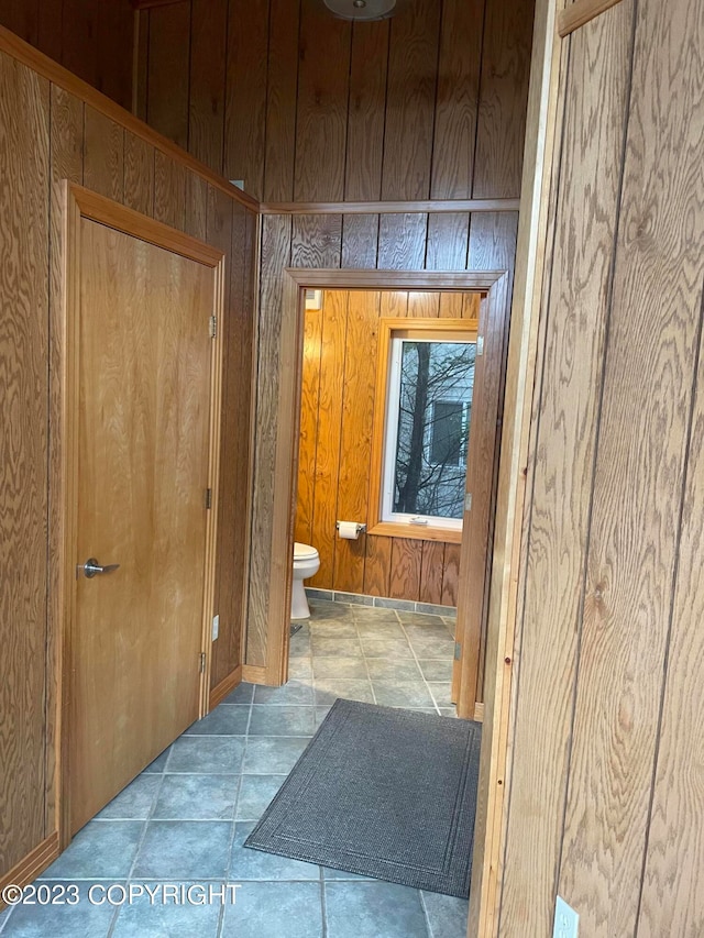 interior space with wood walls, tile flooring, and toilet