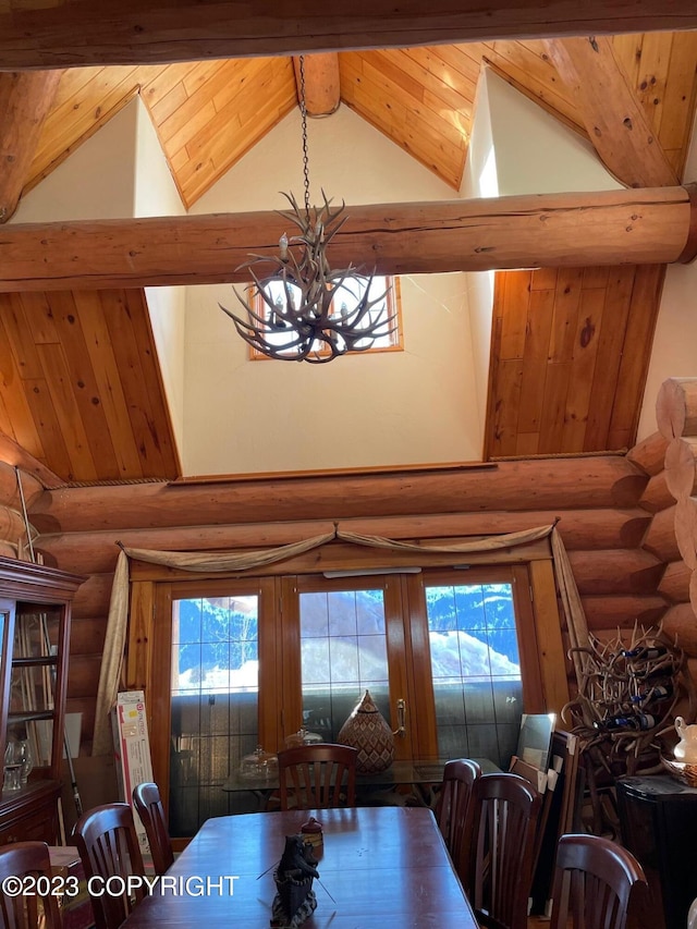 dining room with a notable chandelier, rustic walls, high vaulted ceiling, and beam ceiling