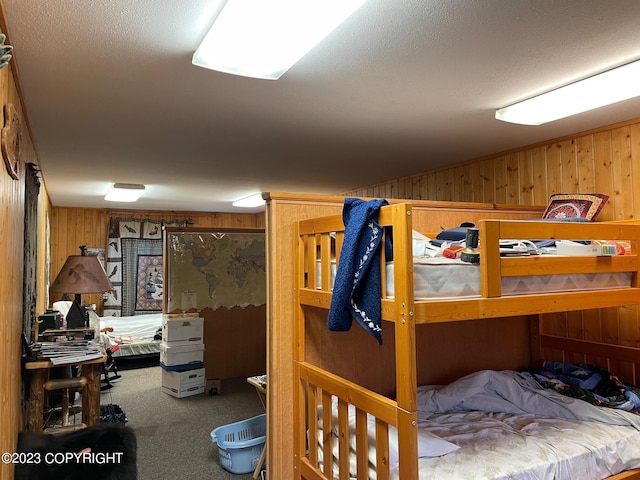 bedroom with carpet flooring, wooden walls, and a textured ceiling