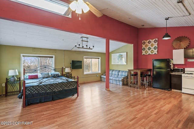 bedroom featuring ceiling fan, black fridge, light hardwood / wood-style floors, and multiple windows