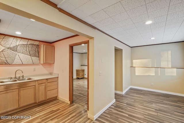 kitchen featuring light brown cabinets, ornamental molding, light hardwood / wood-style flooring, and sink