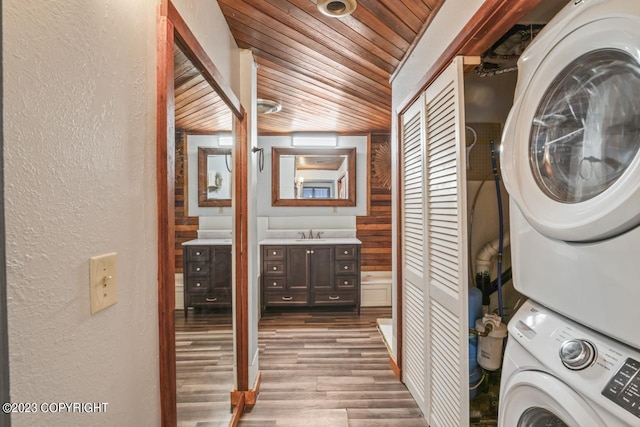 clothes washing area featuring sink, wooden ceiling, stacked washer and clothes dryer, and dark hardwood / wood-style flooring