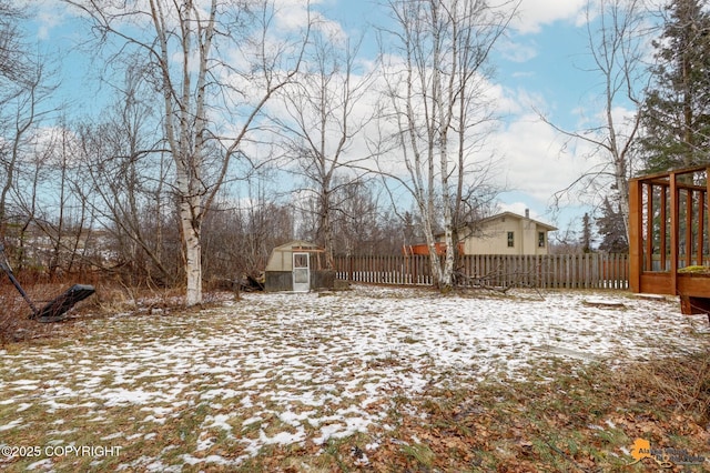 yard layered in snow with an outbuilding and fence