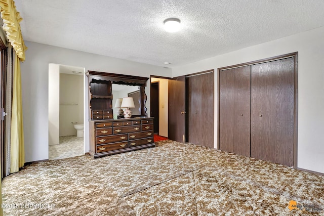 unfurnished bedroom with carpet flooring, a textured ceiling, and two closets