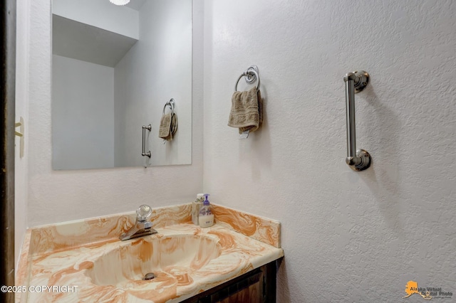 bathroom featuring a textured wall and vanity