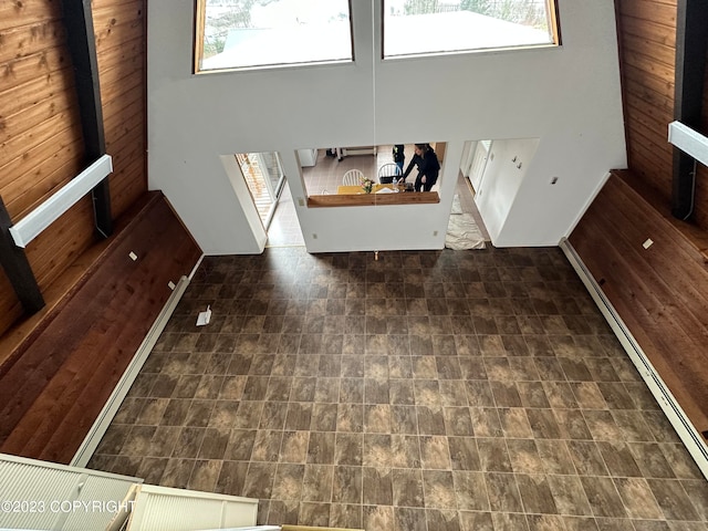 unfurnished living room with a high ceiling, dark tile flooring, and a healthy amount of sunlight