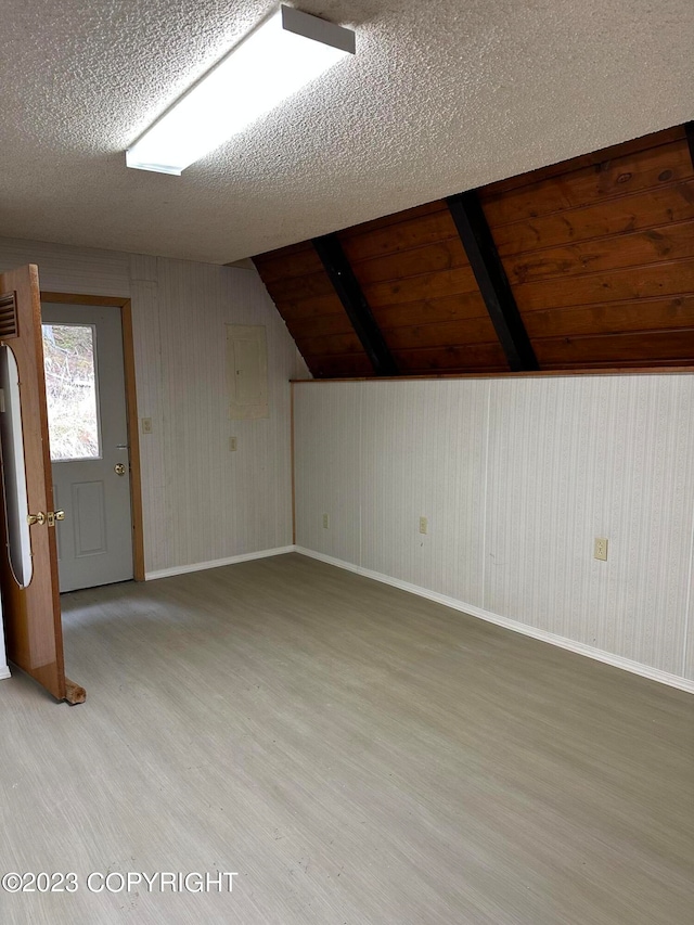 additional living space with wood ceiling, a textured ceiling, light hardwood / wood-style flooring, and vaulted ceiling with beams