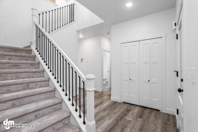 stairs with recessed lighting, wood finished floors, and baseboards