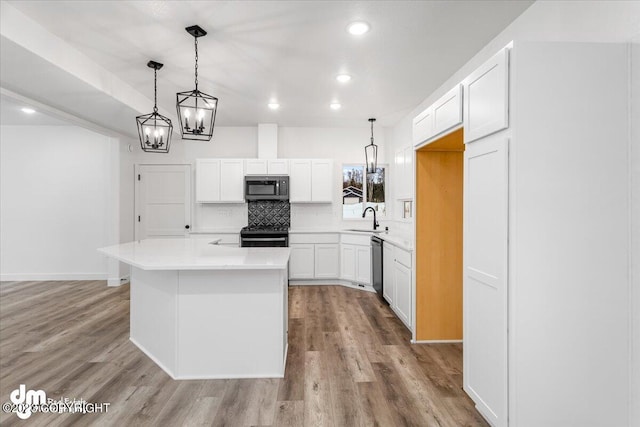 kitchen with black range with gas stovetop, decorative backsplash, light wood-style flooring, stainless steel dishwasher, and a sink