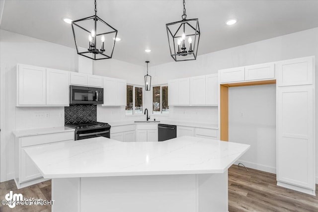 kitchen featuring a sink, black appliances, light wood-style flooring, and white cabinetry