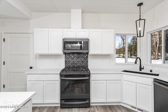 kitchen featuring a sink, stainless steel microwave, light countertops, black range with gas cooktop, and dishwasher