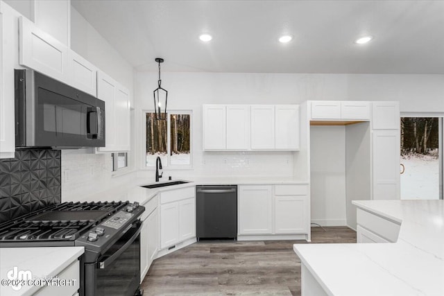 kitchen featuring stainless steel appliances, backsplash, hardwood / wood-style floors, white cabinetry, and pendant lighting